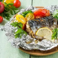 Poisson cuit dans l'aluminium, servi avec des tomates et du persil. Un délice simple et savoureux.
