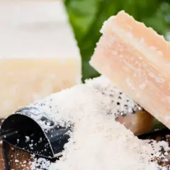 Parmezan, znany z niskiego indeksu glikemicznego, w kawałkach i starty na tarce, z listkami bazylii.
