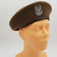 Brązowy beret wojskowy z orłem, jeden z rodzajów czapek wojskowych, prezentowany na manekinie.