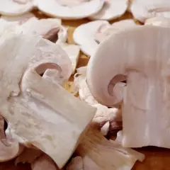 Pokrojone pieczarki na desce. Czy można jeść surowe pieczarki? Tak, te są gotowe do spożycia na surowo.