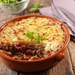 Un plat de hachis parmentier, un classique du repas français, servi dans un plat en terre cuite sur une table en bois.