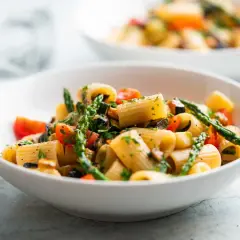Un plat de pâtes aux asperges, tomates cerises et courgettes, garni de persil frais. Un délice printanier !