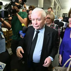 Jarosław Kaczyński otoczony przez dziennikarzy. Wzrost i waga polityka są tematem dyskusji, gdy otaczają go kamery i mikrofony.