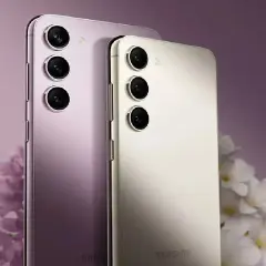 Dwa telefony Samsung z dobrym aparatem, jeden fioletowy, drugi kremowy, na tle kwiatów.