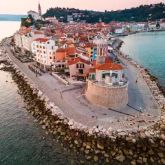 Piran plaża: malownicze miasteczko na półwyspie, z kolorowymi domami, kamienną promenadą i wieżą kościelną górującą nad Adriatykiem.