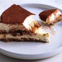 Una fetta di tiramisù, con cacao in polvere, su un piatto. La ricetta perfetta per un dolce cremoso e goloso.