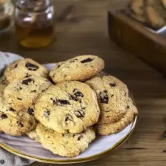 Montón de galletas con pepitas de chocolate recién horneadas, listas para disfrutar con un vaso de leche.