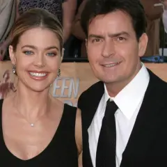 Charlie Sheen i jego żona, Denise Richards, uśmiechają się do aparatu na czerwonym dywanie.