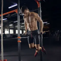 Mężczyzna wykonuje pompki na poręczach w siłowni CrossFit.