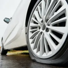 Un clou dans pneu, la voiture est à plat sur la route mouillée.