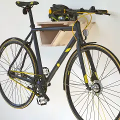 Schwarzes Fahrrad mit gelben Akzenten hängt an einer selbstgebauten Holz-Fahrrad-Wandhalterung. Helm liegt auf der Ablage.