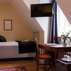 A hotel room with a bed, desk, chair, and a TV mounted on the wall.