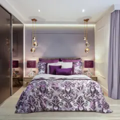 Elegancka, fioletowa sypialnia z bogato zdobioną pościelą, lustrzaną szafą i nowoczesnymi lampami.