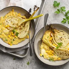 Deux bols de polenta crémeuse avec du fenouil rôti, du maïs et du persil.