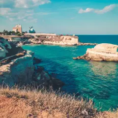 Côte rocheuse italienne aux eaux turquoise, avec des falaises et des formations rocheuses dans la mer.
