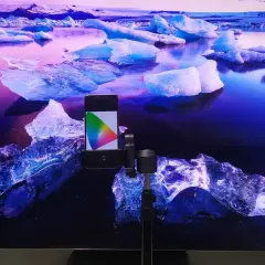 Telefon z kolorowym wzornikiem na tle lodowca, przygotowanie do kalibracji telewizora.