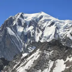Majestatyczne wejście na Mont Blanc. Śnieżne szczyty i skaliste zbocza pod błękitnym niebem.