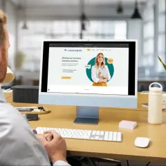 Mężczyzna pracuje przy komputerze, na ekranie widoczna strona internetowa agencji ubezpieczeniowej.