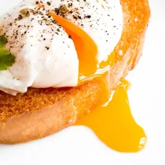 Un œuf mollet parfait, avec son jaune coulant, sur une tranche de pain grillé. Le temps de cuisson est idéal pour ce délice.