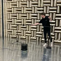 Hombre ajustando micrófonos en cámara anecoica para medir la unidad de potencia acústica de un altavoz.