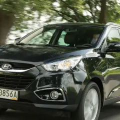 Czarny Hyundai ix35 2.0 benzyna w ruchu, z zielenią drzew w tle.