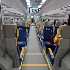 Wnętrze szynobusu na trasie Lublin - Zamość. Puste, niebieskie siedzenia z żółtymi uchwytami czekają na pasażerów.