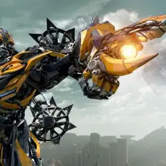 Bumblebee, jeden z robotów Transformers, celuje z działka na tle mglistego miasta i latających maszyn.