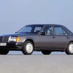 Szary Mercedes-Benz W124, symbol najbardziej niezawodnych samochodów, stoi na pustej drodze.