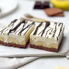 Zwei Stücke Bananensplit Torte mit Schokoladenboden, Bananenscheiben und cremiger Füllung, garniert mit Schokoladensauce.