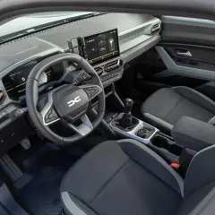 Wnętrze Dacia Duster: kierownica, ekran multimediów, dźwignia zmiany biegów i fotele.