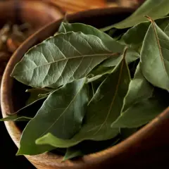 Hojas de laurel secas en un cuenco de madera, listas para dar sabor a guisos y estofados.