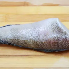 Fragment ryby nototenia, znanej też jako patagońska, na drewnianej desce.
