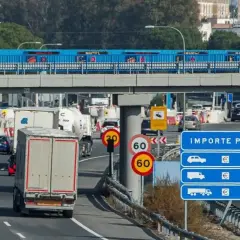 Tráfico lento en peaje con señales de límite de velocidad y de carril estrecho. Los vehículos esperan para pagar el importe del peaje.