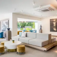 Salón moderno con sofás modulares, sillones azules y arte marino. El cartel "Occidental Puerto Banús" se ve al fondo.