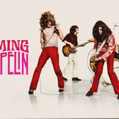 Zespół Led Zeppelin w akcji. Wokalista z mikrofonem, gitarzysta, basista i perkusista tworzą potężne brzmienie.