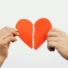 Mani che tengono un cuore rosso spezzato. Ho perdonato un tradimento ma non riesco a dimenticare.