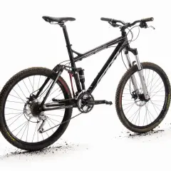 A black full-suspension mountain bike, the "Felt Virtue," stands ready for adventure. Its knobby tires are dusted with dirt, hinting at recent trails.