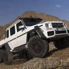 Biały Mercedes G63 AMG 6x6 z sześcioma kołami na skalistym pustynnym terenie.