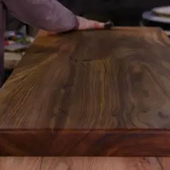 Main d'artisan polissant un plateau en bois exotique pour un entretien intérieur parfait.