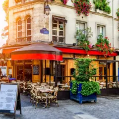 Un caffè parigino con tavolini all'aperto, fioriere rigogliose e un'atmosfera accogliente. Il dehors, in questo contesto, è un invito a godersi la vita.