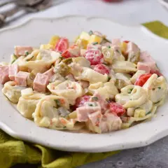 Prosta sałatka z tortellini, szynką, pomidorkami i ogórkiem konserwowym, polana kremowym sosem.