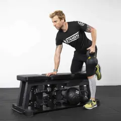 Homme effectuant un exercice de tirage avec kettlebell sur un banc de musculation.