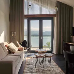Przytulny pokój z widokiem na jezioro w hotelu Lake Hill Resort & Spa w Karkonoszach. Sofa, stoliki kawowe i krzesło motylkowe tworzą komfortową przestrzeń.