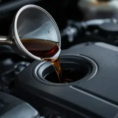 Olja hälls ner i en bilmotor. Oljan består av basolja och tillsatser som smörjer och skyddar motorn.
