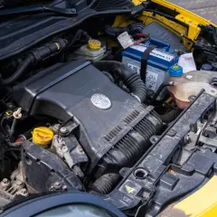 Silnik żółtego Alfa Romeo MiTo. Widoczny akumulator, obudowa filtra powietrza z logo marki i płyny eksploatacyjne.