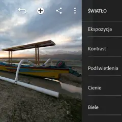 Łódź na plaży o zachodzie słońca, edytowana w trybie camera raw. Kontrolki ekspozycji, kontrastu, podświetleń, cieni i bieli.