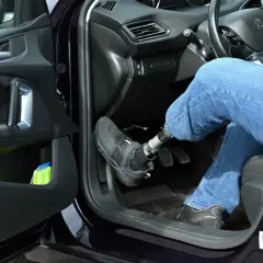 Autofahren mit Orthese links: Person mit Prothese am linken Bein bedient Automatik-Auto.