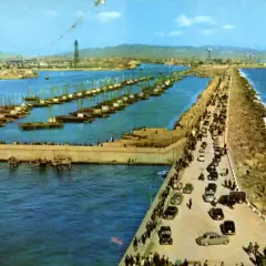 El rompeolas de Burela, con barcos alineados y coches circulando, protege la costa de las olas.