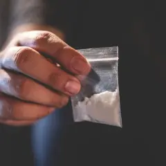 Dłoń trzyma woreczek z białym proszkiem. To może być związane z chemsex, czyli używaniem substancji psychoaktywnych w celu wzmocnienia doznań seksualnych.