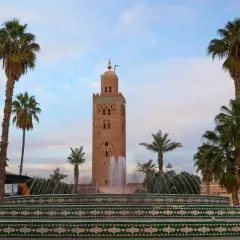 Torre Koutoubia y fuente en Marrakech, un lugar perfecto para tu visita de Marrakech en 3 días. Palmeras y cielo azul.